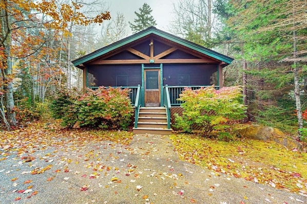 A lodge with a wooden exterior, a front porch, and a staircase leading to the entrance.