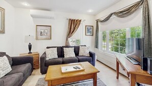 A living room with a sofa, coffee table, and a TV on a wooden stand. - Perfect Cottage Near Downtown & Glen Mary Park w/ Full Kitchen, Free WiFi, More (Bar Harbor)