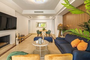 Un salon moderne avec une cheminée, un canapé, une table basse et un coin repas.