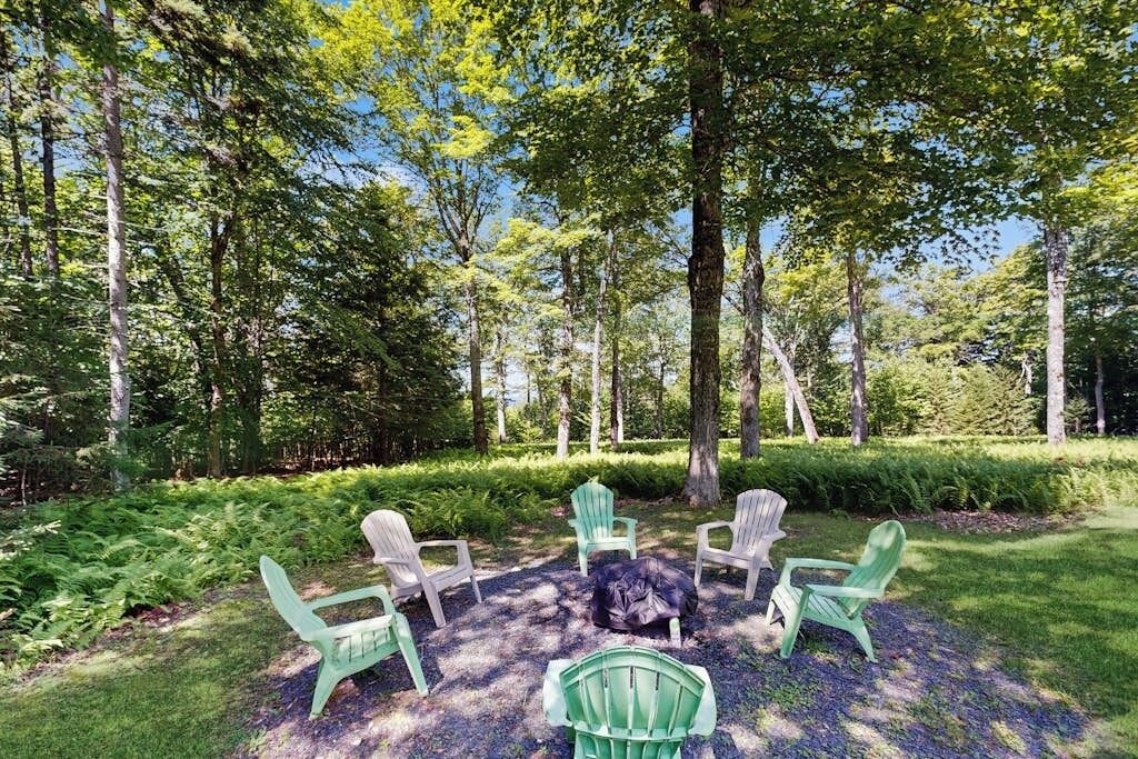 A circular seating arrangement with chairs around a central fire pit in a forested area.