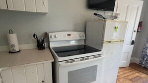 A compact kitchen with a stove, oven, and a small refrigerator. - Downtown Studio w/ Full Kitchen & Shared Porch - Walk Everywhere in Town (Castine)