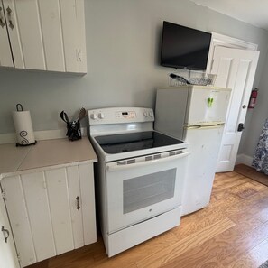 Una cocina compacta con estufa, horno y un refrigerador pequeño.