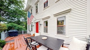 A covered patio with a table and chairs, an American flag, and a red door.