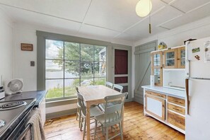 A kitchen with a dining table, chairs, a stove, and a refrigerator. - Historic riverfront home with boathouse & private dock - dogs OK (Boothbay)
