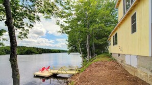 Une propriété au bord du lac, dotée d’un quai, d’un bâtiment jaune et d’une zone boisée.