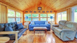 L’intérieur d’un chalet accueillant, avec des murs en bois, un canapé bleu, un fauteuil inclinable gris et une table basse en bois.
