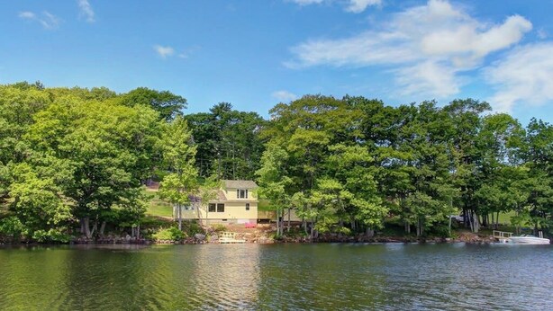 Une propriété au bord du lac, comprenant une maison, des arbres et un quai.
