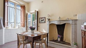 Un comedor con una mesa, sillas, chimenea y un ventanal con cortinas.