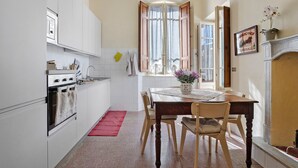 Una cocina con armarios blancos, una mesa de comedor de madera y una alfombra roja.