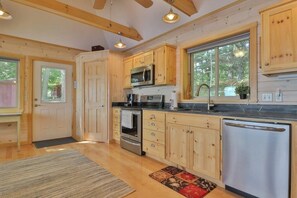 A modern kitchen with wooden cabinets, stainless steel appliances, and large windows.