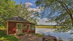 A small cabin by a lake with a picnic table in front. - Luxe Bayfront Cabin w/ Stunning Views & Shared Dock- Ideal for Hunting & Fishing (Bowdoinham)