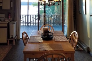 A dining area with a table set for four, a view of the outdoors, and a wooden deck. - Lakefront Cabin with Lake Views, Private Dock & Entertainment - Great for Families (Greenville)