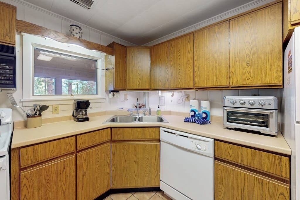 A kitchen with wooden cabinets, a dishwasher, a stove, and a window.
