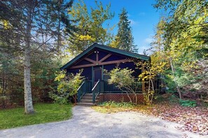 Eine Hütte mit Veranda, umgeben von Bäumen.