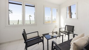 Una habitación con ventanas amplias, una mesa, dos sillas y un sofá.