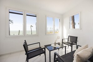 Una habitación con ventanas amplias, una mesa, dos sillas y un sofá.