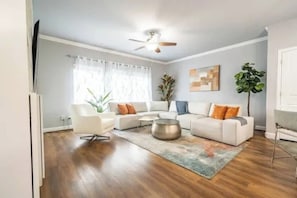 Ein modernes Wohnzimmer mit einem weißen Sofa, einem Couchtisch und einem Deckenventilator.