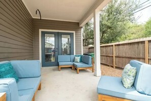 Eine überdachte Terrasse mit zwei blauen Sofas und einem Holztisch.