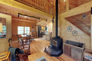 Ein Blockhaus-Interieur mit Essbereich, Küche und Kaminofen.