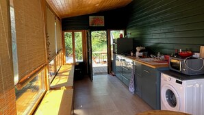 A modern kitchen with a wooden ceiling, a washing machine, and a dining area with a table and chairs. - Wooden beach house for vacations - Le Verdon-sur-Mer (33) (Le Verdon-sur-Mer)