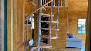 A spiral staircase with a wooden interior, a white sofa, and a window with a view. - Wooden beach house for vacations - Le Verdon-sur-Mer (33) (Le Verdon-sur-Mer)