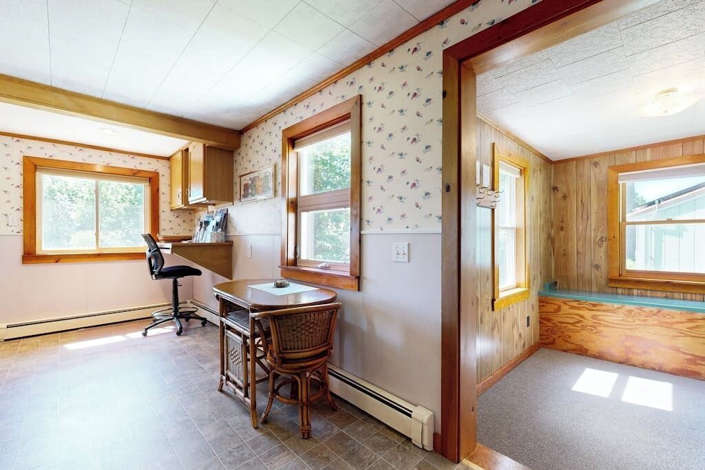 A room with a desk, chair, and large windows.