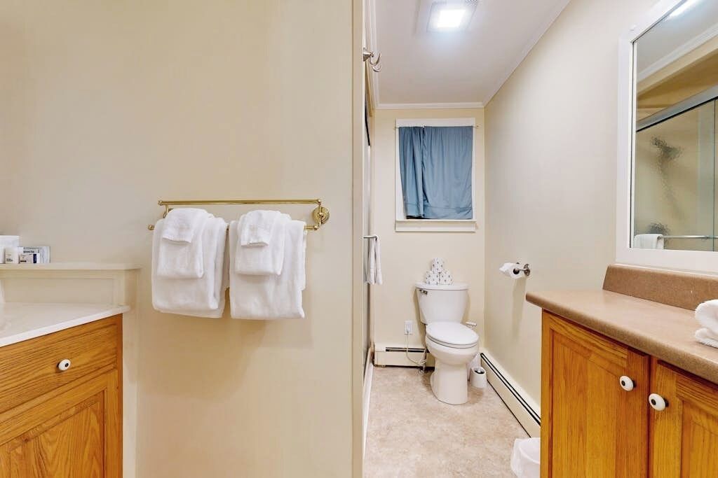 A bathroom with a toilet, a sink, a mirror, and a towel rack.