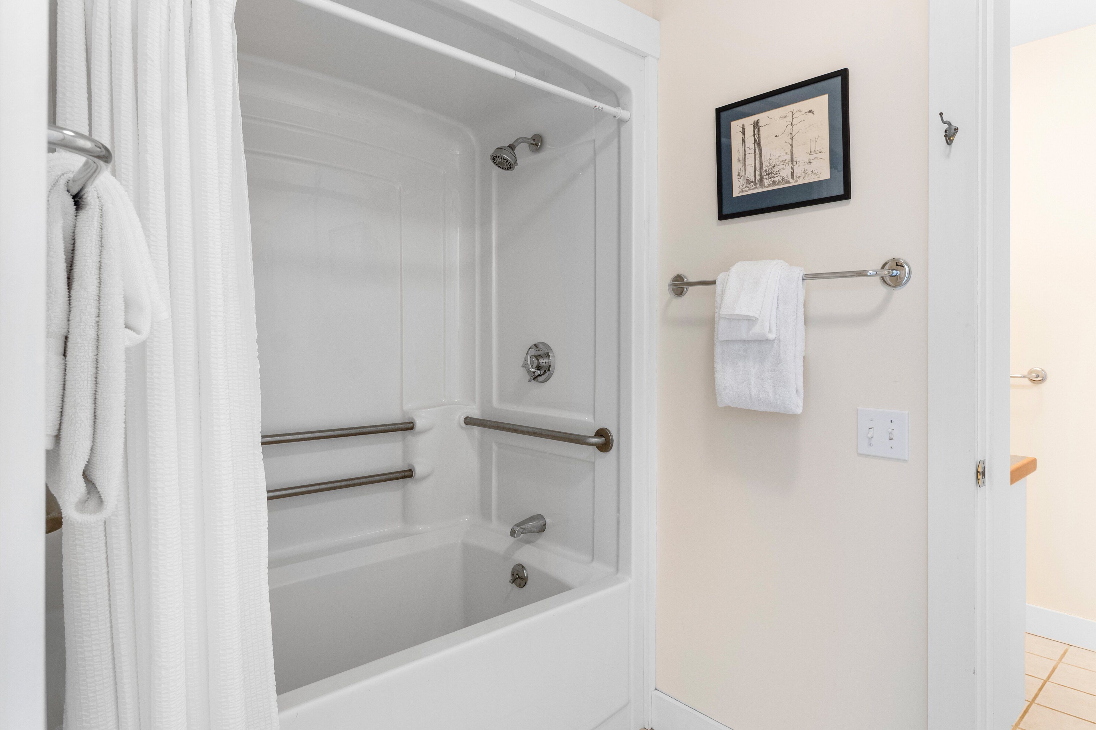 A bathroom with a bathtub, towel rack, and a framed picture on the wall.