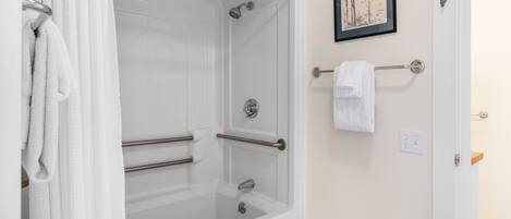 A bathroom with a bathtub, towel rack, and a framed picture on the wall.