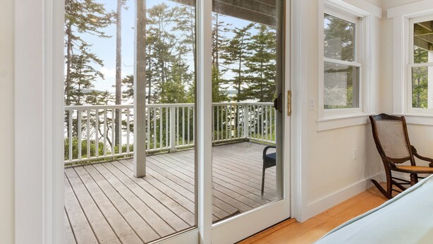 A room with a sliding glass door leading to an outdoor deck with a wooden floor and white railing. - Comfortable bayfront home with beautiful views, large deck & on-site tennis (Seal Cove)