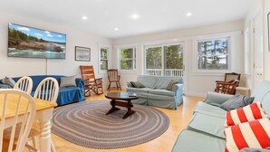 A spacious living room with a dining area, large windows, and a view of the outdoors. - Comfortable bayfront home with beautiful views, large deck & on-site tennis (Seal Cove)