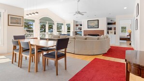 A spacious living room with a dining area, a large window, and a ceiling fan. - Comfortable bayfront home with beautiful views, large deck & on-site tennis (Seal Cove)