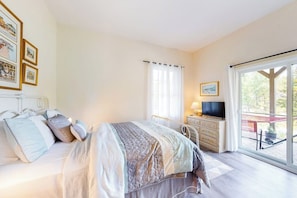 A bedroom with a bed, bedside table, TV, and a window with curtains. - Secluded hilltop home with beautiful Cadillac Mountain view and multiple decks (Bar Harbor)