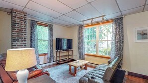 Een woonkamer met een bank, salontafel, tv-meubel en een lamp.