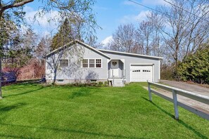 Ein eingeschossiges Haus mit Garage, einer Veranda und einem gepflegten Rasen.