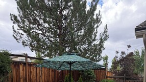 Une terrasse avec une table ronde, quatre chaises et un parasol à motifs.