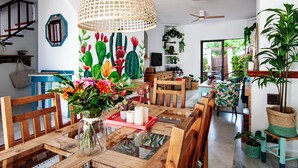 Ein Essbereich mit Holztisch, Stühlen, einer Blumenvase und einer hängenden Lampenschirm aus Bändern.