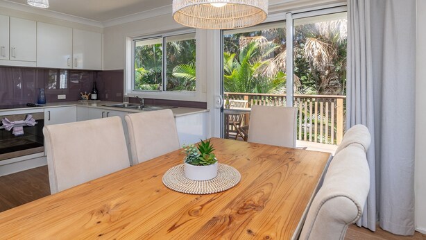 Una cucina moderna con zona pranzo, ampie finestre e un balcone con piante.