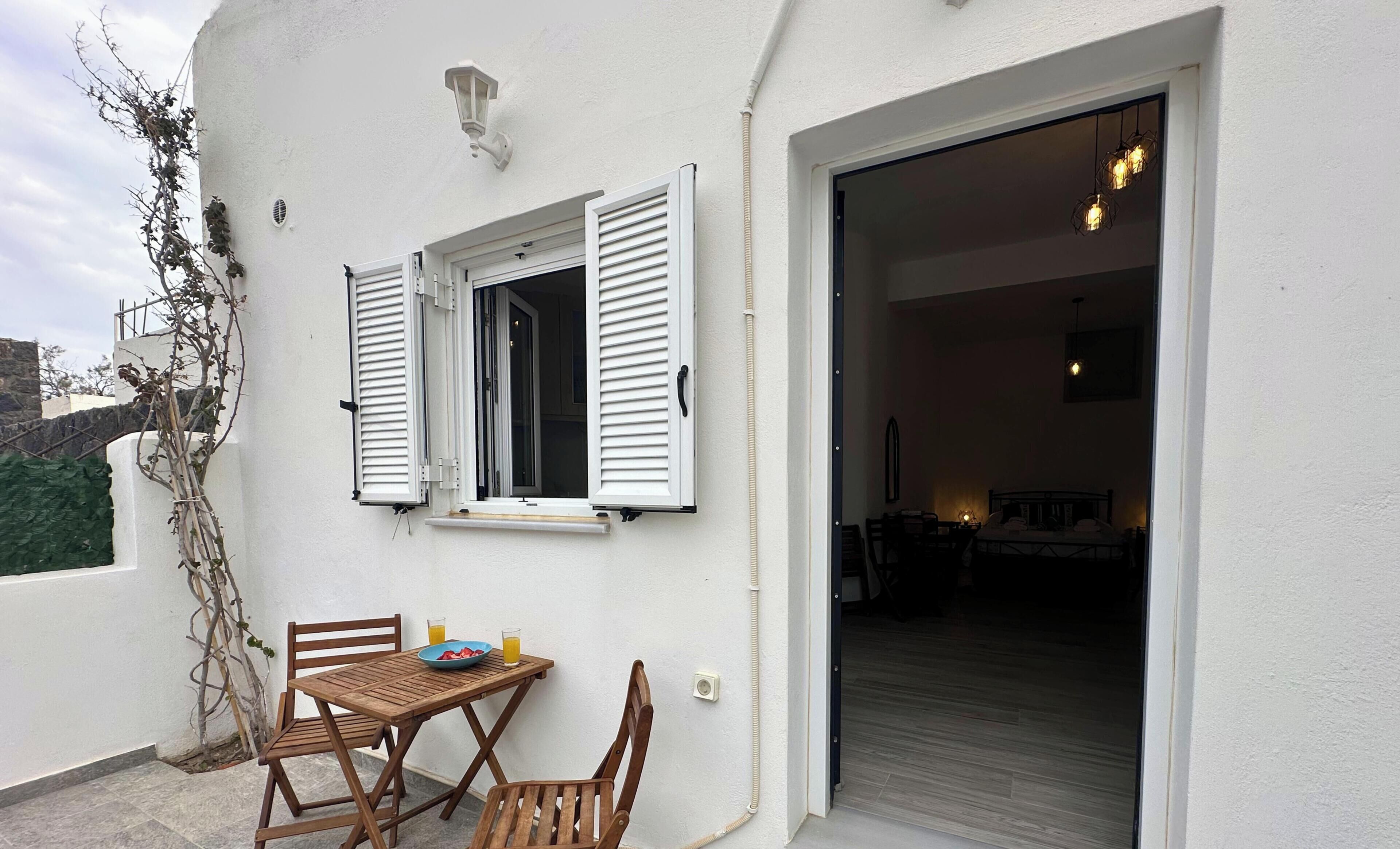 A balcony with a table, chairs, and a bowl of fruit.
