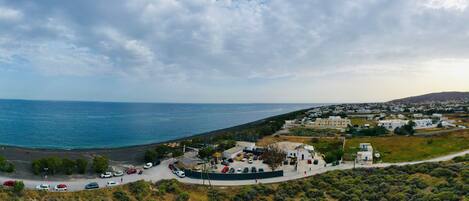A coastal town with a beach, parked cars, and white buildings.
