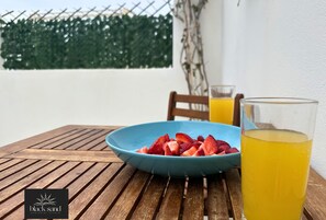 Ein Holztisch mit einer blauen Schüssel voll Erdbeeren und einem Glas Orangensaft.