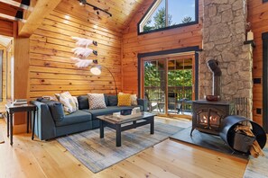 Ein gemütliches Wohnzimmer mit Kamin aus Stein, Holzwänden und einem großen Fenster.