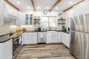 Una cocina moderna con armarios blancos, un refrigerador de acero inoxidable y piso de madera.