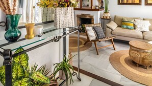A living room with a glass coffee table, a sofa, a fireplace, and a large mirror. - Casa vacacional 'Beachfront Bohochic 2' con balcón, Wi-Fi y aire acondicionado (Estepona)