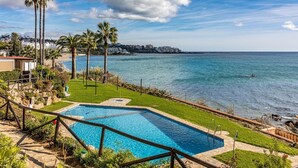 A pool with a view of the sea, palm trees, and a distant shoreline. - Casa vacacional 'Beachfront Bohochic 2' con balcón, Wi-Fi y aire acondicionado (Estepona)