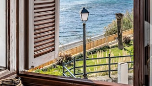 A coastal view through a window with shutters, a lamp post, and a wicker basket. - Casa vacacional 'Beachfront Bohochic 2' con balcón, Wi-Fi y aire acondicionado (Estepona)