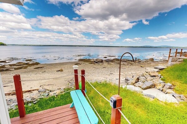A wooden deck with a bench overlooking a rocky shoreline and calm water. - Cozy Studio with Lofted Sleeping Space and Great Water View (Surry)