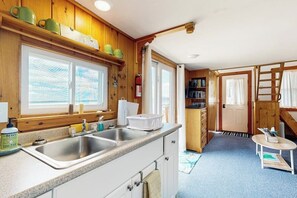Eine Küche mit Holzausstattung, einem doppelten Spülbecken und einem Fenster mit Jalousien.