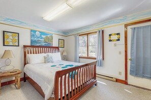 Un dormitorio con cama de madera, dos mesitas de noche, una ventana con cortinas y decoración en la pared.