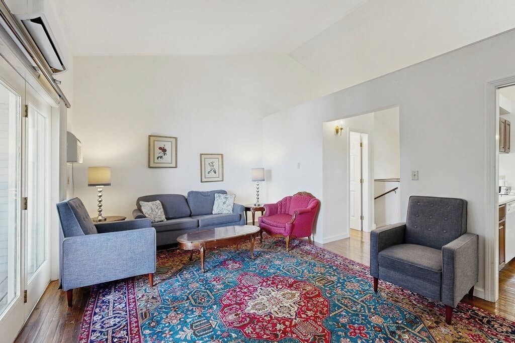 Un salon comprenant un canapé, des fauteuils, une table basse et un tapis à motifs.